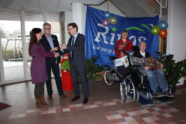 Lilian Bouman, regiomanager bij Rivas, krijgt de sleutel van de rolstoelfiets officieel overhandigd door Jaap Kuipers, bedrijvenadviseur van de Rabobank Drechtsteden.